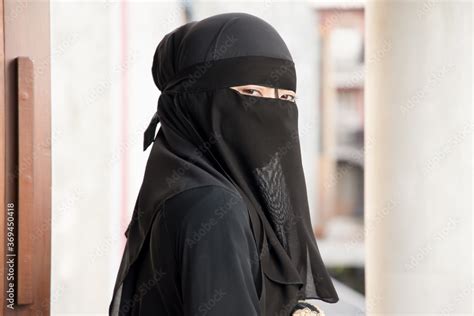 Portrait of Arabian woman looking at you while covering her face with niqab veil, traditional ...