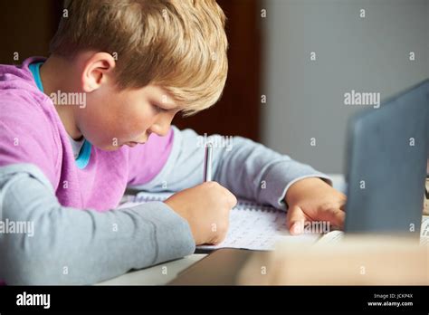 Boy Studying In Bedroom Using Laptop Stock Photo - Alamy