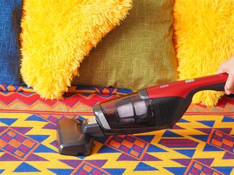 Premium Photo | Cleaning the sofa with a handheld cordless vacuum cleaner