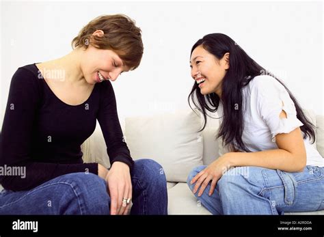 Two women laughing on sofa Stock Photo - Alamy