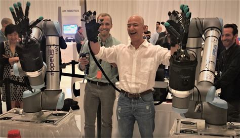 Jeff Bezos gets a laugh out of his round with a robotic arm at re:MARS