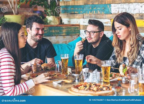 Young People Enjoying Time Together Eating Burgers and Pizza at Restaurant Stock Image - Image ...