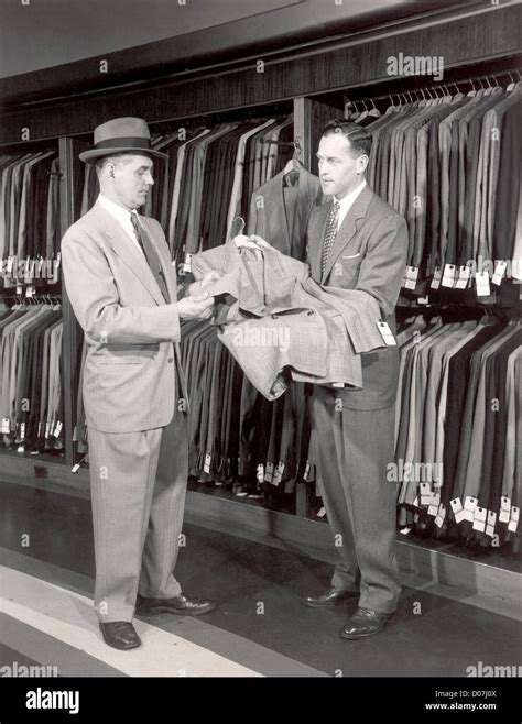 Salesman showing man suit in store Stock Photo - Alamy