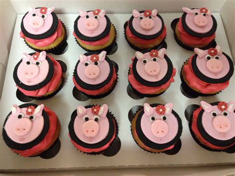 twelve cupcakes with pink and black frosting in a box, decorated with pigs