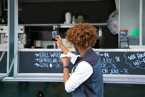 Black faceless man with burger taking selfie near food truck · Free Stock Photo