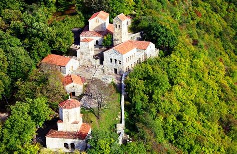 an aerial view of a castle in the middle of some trees and bushes with red roof tops