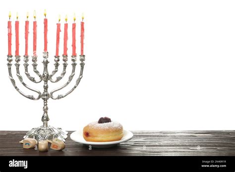 Silver menorah near sufganiyah and dreidels with symbols Nun, He, Pe, Gimel on white background ...