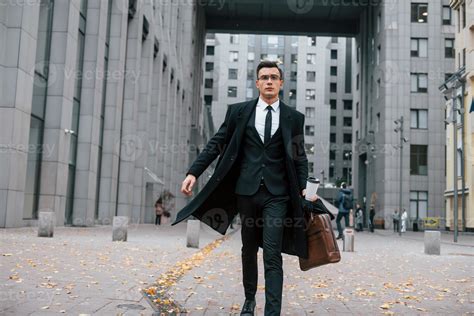 Going to work. Businessman in black suit and tie is outdoors in the ...