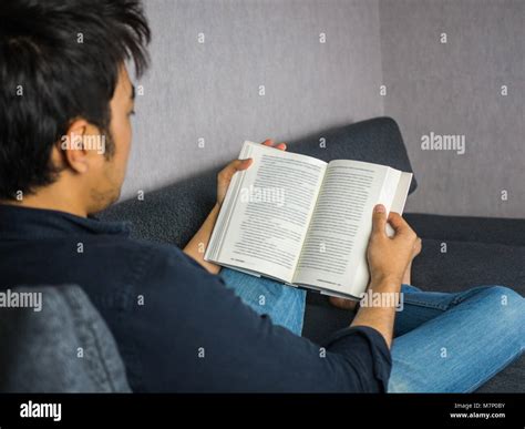 Man reading book on sofa at home Stock Photo - Alamy