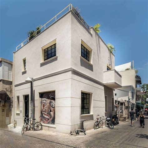 a white building with bicycles parked in front of it and people walking ...