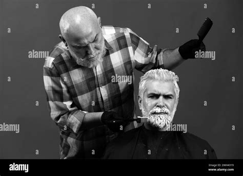 Bearded man coloring hair. Hair salon, hair coloring man. Attractive senior barber doing a ...