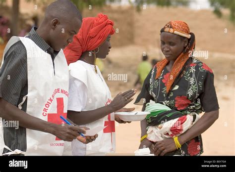 Croix Rouge volunteers explaining how supplementary food should be administered to a mother in ...