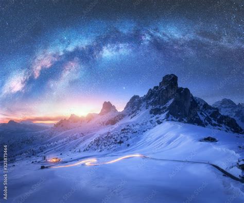 Milky Way over snowy mountains and blurred car headlights on the ...