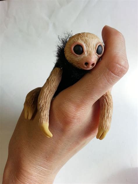 a hand holding a small toy sloth on top of it's palm,