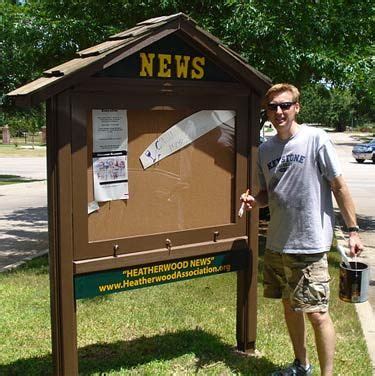 a man standing next to a mailbox on the side of a road with newspaper in it