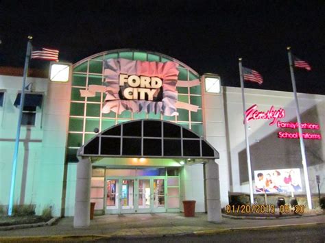 the front entrance of a building with flags flying in the wind and lights on at night