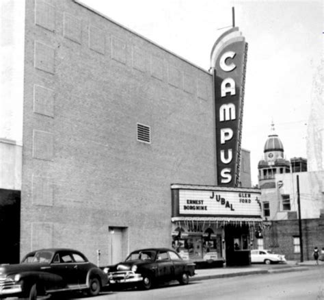 an old theater with cars parked in front and the marquee on the side