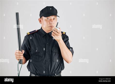 Studio photo of serious police officer raising hand with truncheon and ...