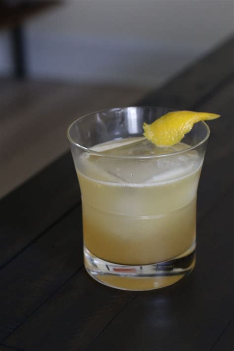 a close up of a drink on a table with a lemon wedge in the glass