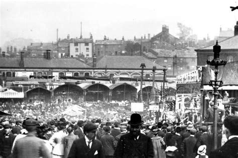 an old black and white photo of many people in the street with buildings behind them