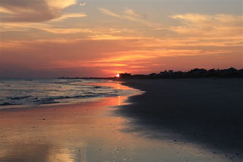 the sun is setting over the water at the beach