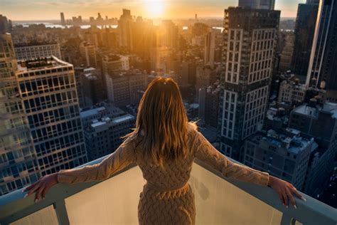 Rich woman enjoy the sunset standing on the balcony at luxury apartments in New York City ...