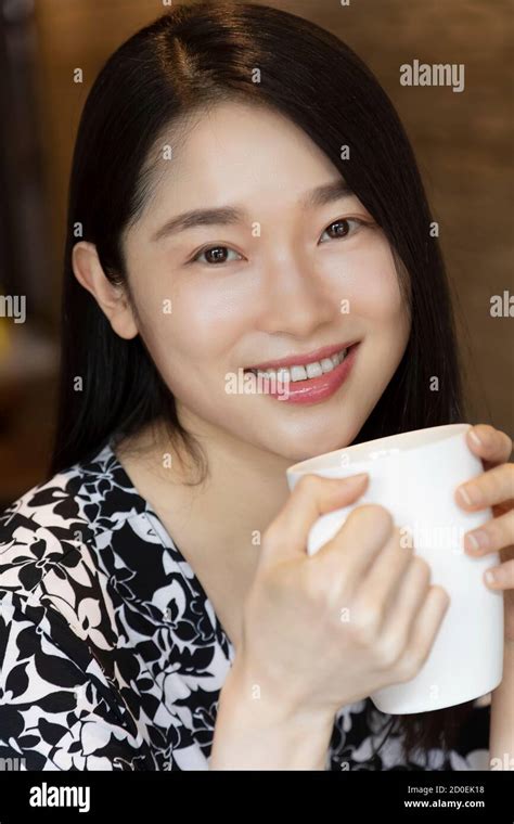 Chinese American woman holding a mug of coffee in a coffee shop with copy space Stock Photo - Alamy