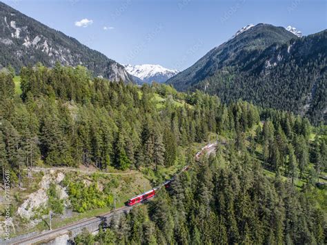 Bernina Express on the railway in a forest, aerial view. Unesco World Heritage Stock Photo ...