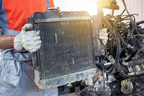 Auto mechanics holding broken car radiator in auto service, technician doing the checklist for ...