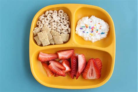 a yellow tray with strawberries, cereals and pretzels on the side