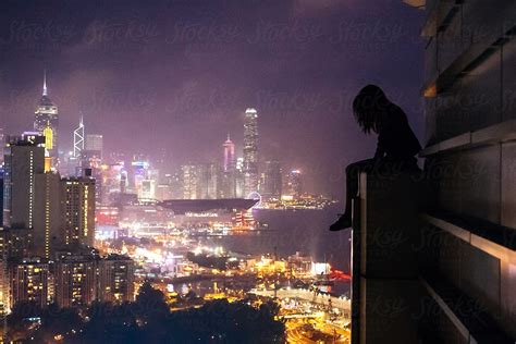 "Girl Sits On Edge Of A Building Rooftop Overlooking Hong Kong" by ...