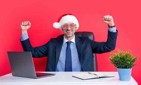 Premium Photo | Successful mature man wear red santa claus hat and party glasses in business office