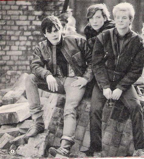 an old black and white photo of two men sitting on top of a pile of bricks