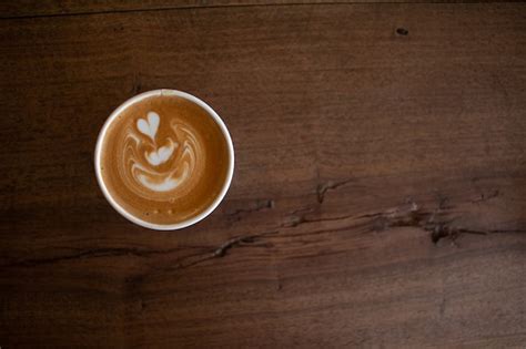 Premium Photo | Piccolo latte art in paper cup on wooden desk