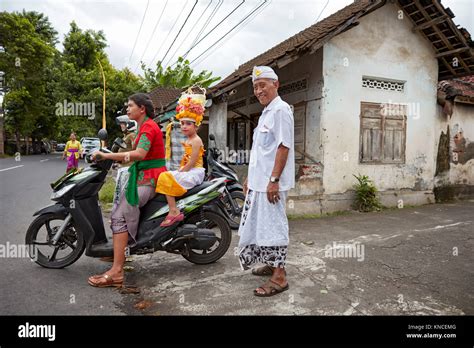 People wearing traditional Balinese clothing go to a local temple near ...