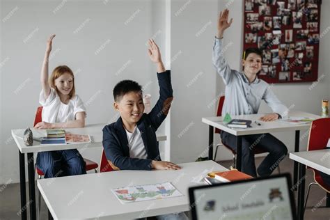 Premium Photo | Children raising their hands in a classroom