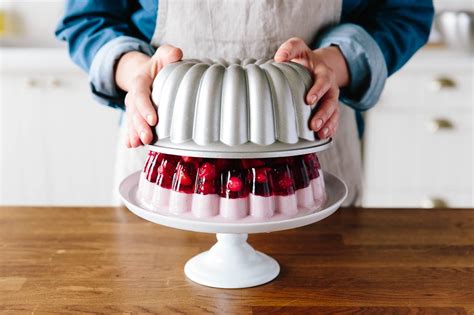 a person is holding a cake with raspberries on it and the icing has been frosted