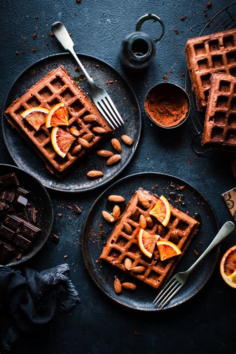 three plates topped with waffles covered in orange slices and nuts next ...