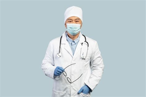 Premium Photo | Confident mature korean man doctor in white coat protective gloves mask takes ...