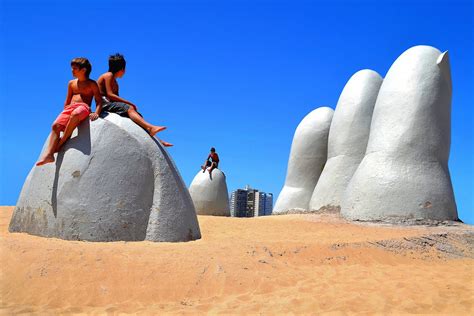 Boys Sitting on La Mano, The Hand, on Brava Beach in Punta del Este, Uruguay - Encircle Photos