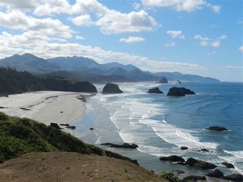 an ocean view with mountains in the distance and water on the beach at the far end