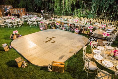 a large wooden dance floor surrounded by tables and chairs with pink flowers on the table