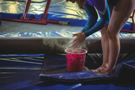 Girl gymnast applying chalk powder on her hands before practicing - Oman Gymnastics Academy