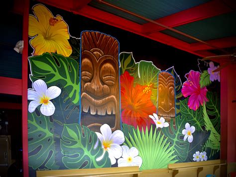 the wall is decorated with colorful flowers and tiki masks on it's sides