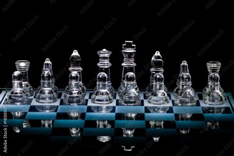 Full Set of Glass Chess Pieces Standing on a Reflective Glass Chessboard with Black Background ...