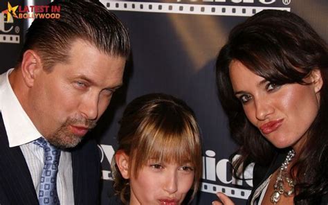 a man, woman and child standing in front of a red carpet with a sign