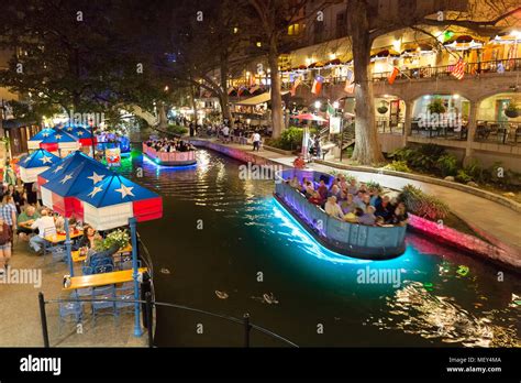 San Antonio Texas river walk at night - a tourist boat on the San Antonio River, the riverwalk ...