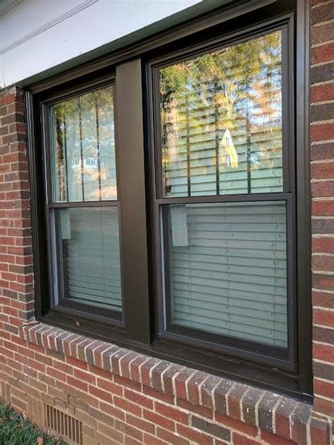 Bronze double hung windows with vertical grids in top sashes and bronze aluminum capping around ...