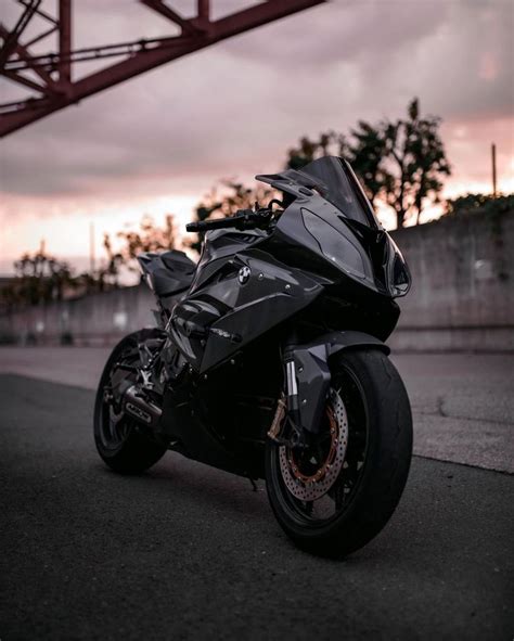 a black motorcycle parked on the street in front of an overpass at ...