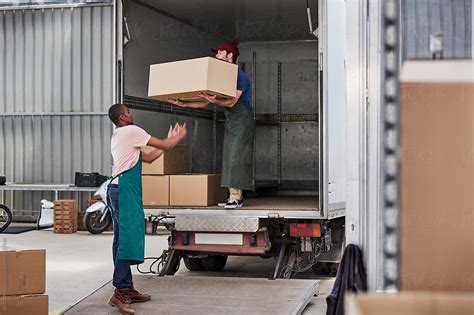 "Workers Unloading Cardboard Boxes From Truck Outside Greenhouse" by ...